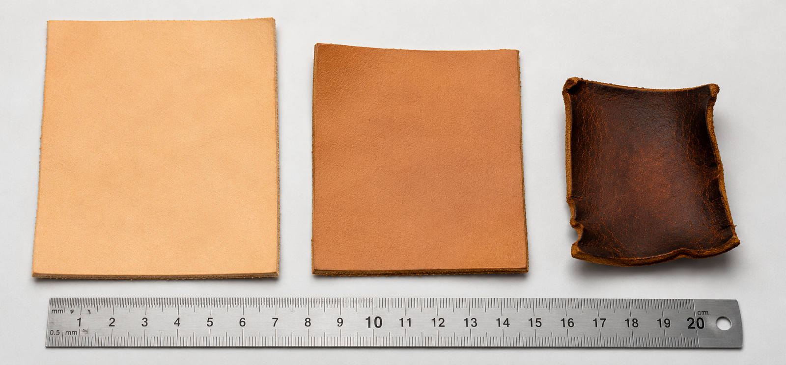 Three vegetable-tanned leather squares arranged beside a metal ruler on a white background showing a large pale untreated sample on the left, a moderately smaller and slightly darker hardened sample in the center, and a significantly shrunken dark brown curled and distorted overheated sample on the right