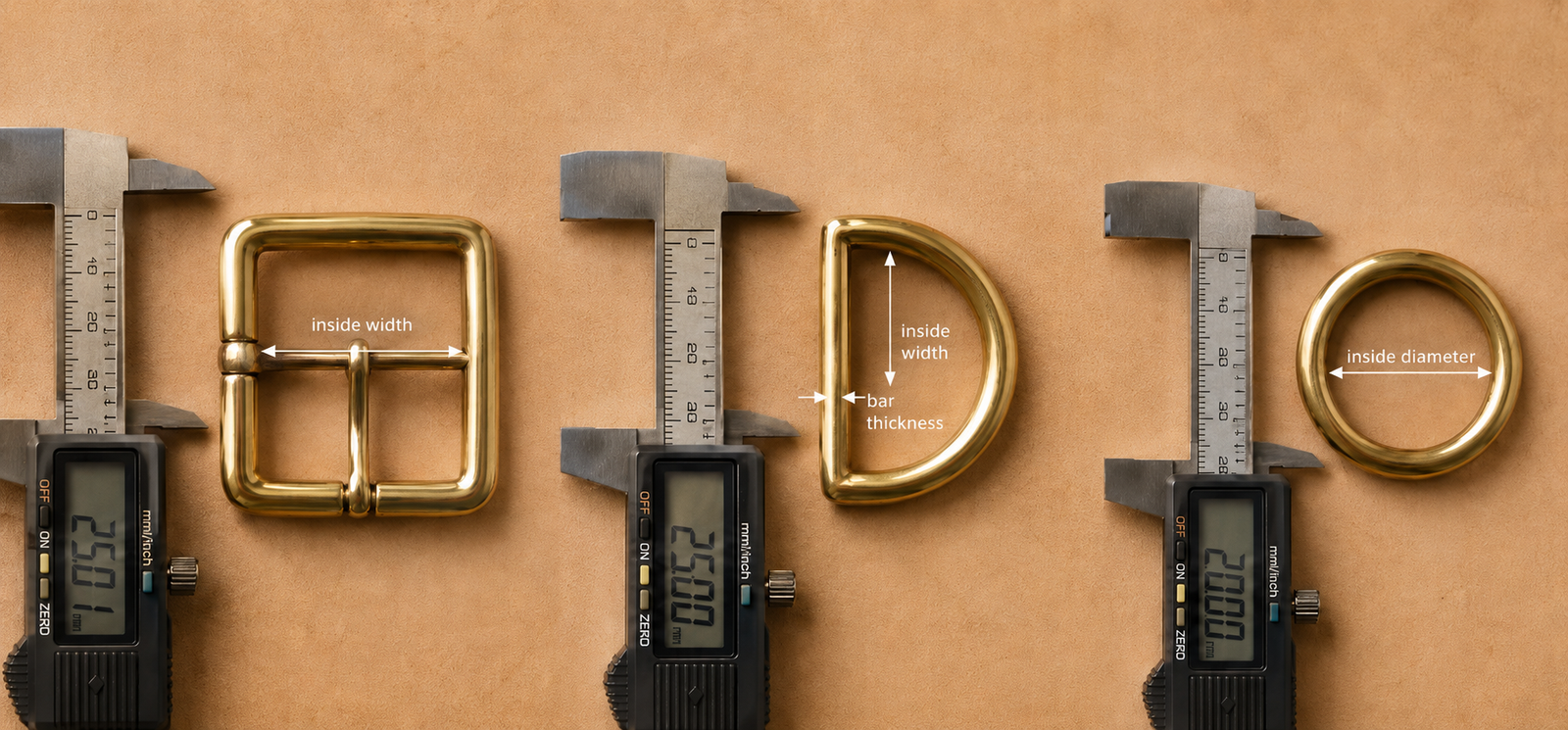 Overhead flat-lay of a brass center-bar buckle, a brass D-ring, and a brass O-ring each measured by a digital caliper on a tan suede leather background with white arrow labels showing inside width, bar thickness, and inside diameter
